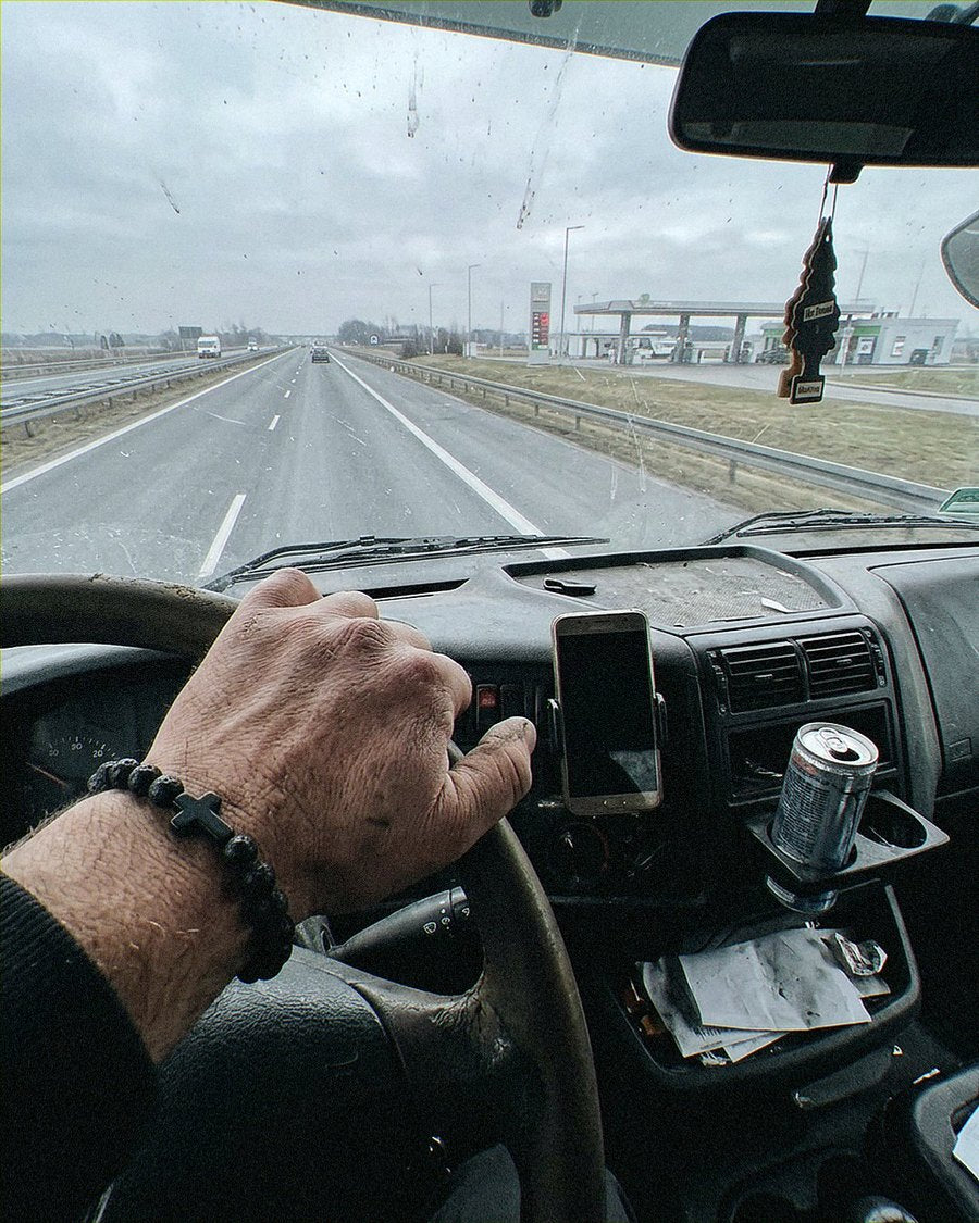 Dłoń kierowcy ciężarówki na kierownicy z bransoletką z lawy