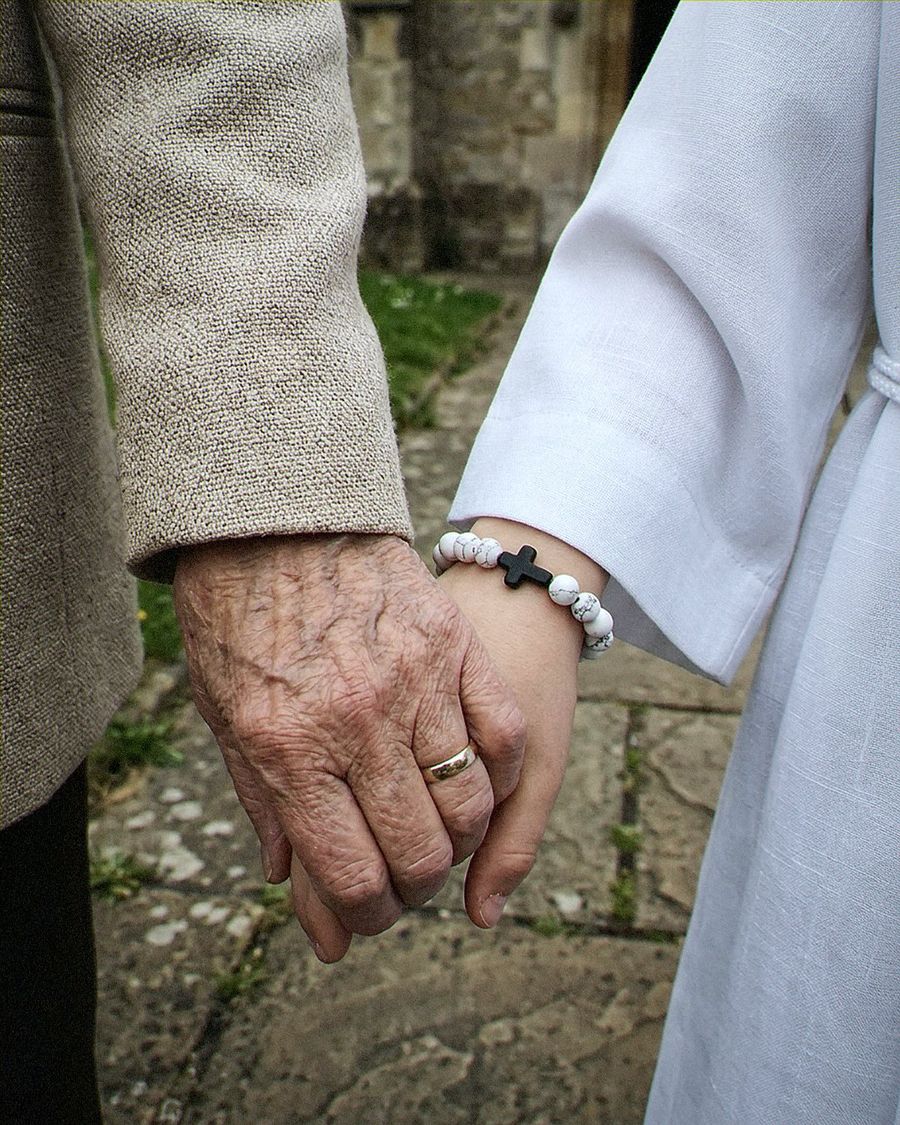 Babcia trzyma dłoń wnuka w dniu komunii
